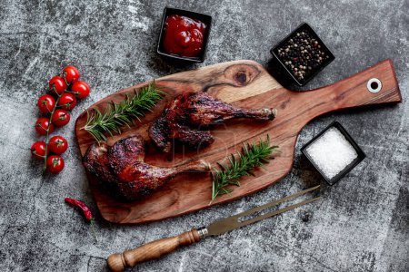 Téléchargez les photos : Grilled chicken legs with spices and herbs on black background - en image libre de droit