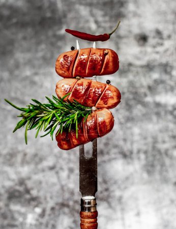 Photo for Grilled sausages with rosemary on fork - Royalty Free Image