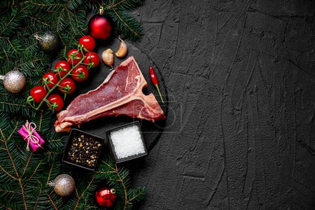 Foto de Concepto de comida navideña. Carne cruda con especias y decoraciones navideñas sobre fondo rústico - Imagen libre de derechos