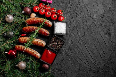 Téléchargez les photos : Saucisses grillées de Noël aux épices sur fond de pierre avec décorations de Noël. Espace de copie - en image libre de droit
