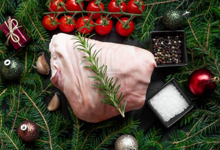 Foto de Carne de cerdo cruda con especias y decoración navideña en superficie negra - Imagen libre de derechos
