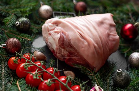 Foto de Carne de cerdo cruda con especias y decoración navideña en superficie negra - Imagen libre de derechos