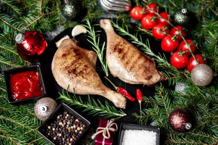 Photo for Grilled ducks legs with herbs, spices and Christmas decorations on stone backrgound - Royalty Free Image