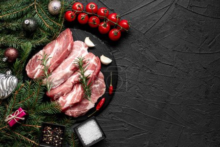 Foto de Filetes de cerdo crudos con decoraciones navideñas sobre fondo de piedra - Imagen libre de derechos