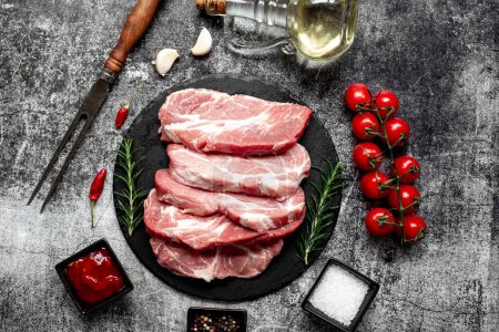 Photo for Raw pork steaks with rosemary and spices on stone background - Royalty Free Image