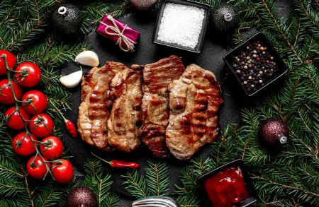 Photo for Grilled pork steaks with Christmas decorations on stone background - Royalty Free Image