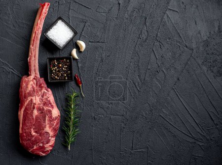 Téléchargez les photos : Tomahawk cru steak et épices sur fond de pierre noire - en image libre de droit