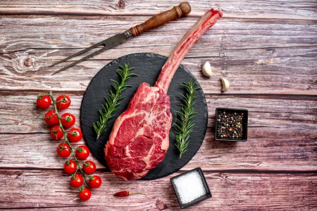 Photo for Raw Tomahawk steak and spices on wooden table background - Royalty Free Image