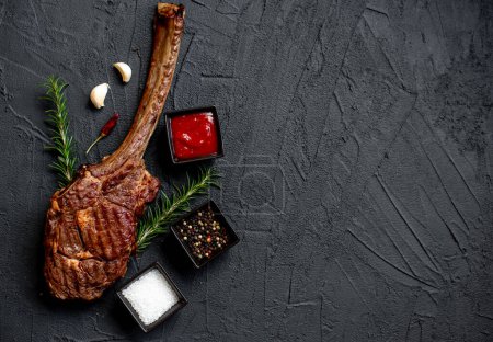 Téléchargez les photos : Tomahawk grillé steak et épices sur fond de pierre noire - en image libre de droit