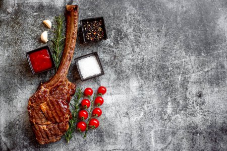 Photo for Grilled Tomahawk steak and spices on grey stone background - Royalty Free Image