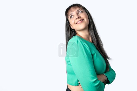 Photo for Pretty Latin woman with her arms crossed and looking up in lateral position on white background. Copy space on left side - Royalty Free Image