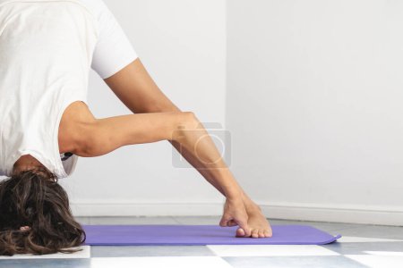 Téléchargez les photos : Close up image of woman doing Prasarita Padottanasana yoga pose. Copy space on the right for advertisement - en image libre de droit