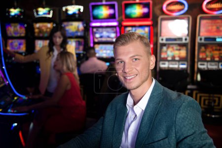 Gut gekleideter Mann spielt Automat im Casino und feiert