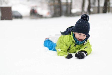 Photo for Little Boy Having Fun and Playing With Snow Outdoors During Snowfall - Royalty Free Image