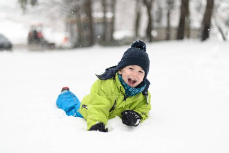Photo for Little Boy Having Fun and Playing With Snow Outdoors During Snowfall - Royalty Free Image