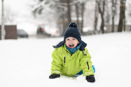 Photo for Little Boy Playing in the Snow Outside During a Snowfall - Royalty Free Image