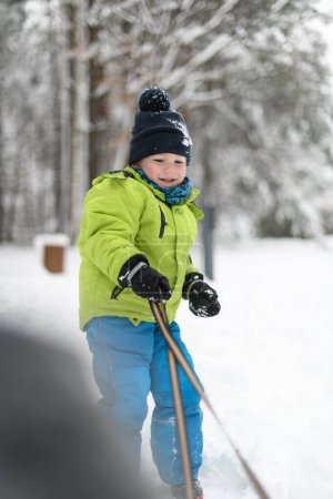 Photo for Little Boy Pulling a Sled in the Snow Outside During a Snowfall - Royalty Free Image