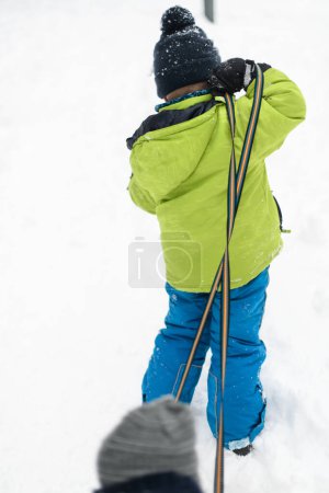 Photo for Little Boy Pulling a Sled in the Snow Outside During a Snowfall - Royalty Free Image