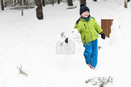 Photo for Little Boy Playing in the Snow Outside During a Snowfall - Royalty Free Image
