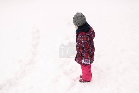 Photo for Little Girl Playing in the Snow Outside During a Snowfall - Royalty Free Image