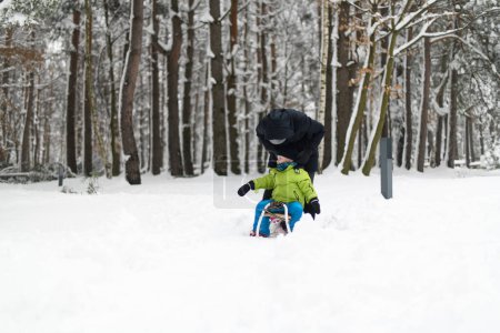 Photo for Joyful Boy in Warm Clothes Happily Playing With Mother Sledding - Royalty Free Image