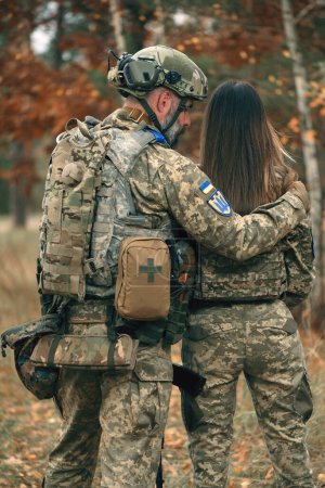 Ukrainian soldiers man and woman dressed military uniform at front line. Couple in love at war during russian military invasion of Ukraine. Love, togetherness and support concept. Rear view