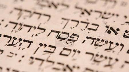 Page of old worn shabby jewish book Torah. Snippet Hebrew Bible text that translates in english: offer the Passover sacrifice to Jehovah. Selective focus on word Pesach. Paschal ritual. Closeup-stock-photo