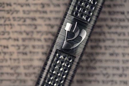 Mezuzah case laying on blurred parchment with Jewish prayer Shema Yisrael in hebrew, mezuzah commandment. Symbol of judaism. Closeup. Selective focus