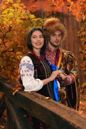 Photo for Young couple dressed traditional ukrainian clothing. Serious cossack man and smiling woman in embroidered costumes outdoors. Vintage outfit - Royalty Free Image
