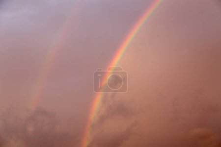 Amazing background with rainbow and clouds. Rainbow at sunset.