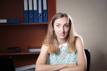 Photo for Female emotional portrait in the office. The woman looks at the camera and smiles thoughtfully. Close-up. - Royalty Free Image
