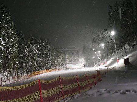 Téléchargez les photos : Illuminated night skiing track with a single skier - en image libre de droit