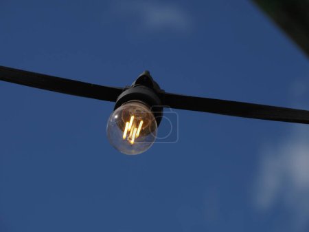 Photo for A garland of LED lights with a transparent bulb on a sky background is turned on - Royalty Free Image