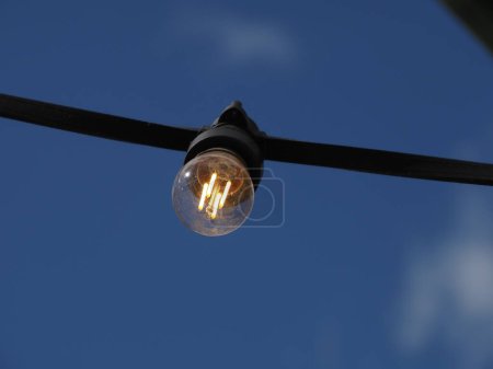 Photo for A garland of LED lights with a transparent bulb on a sky background is turned on - Royalty Free Image