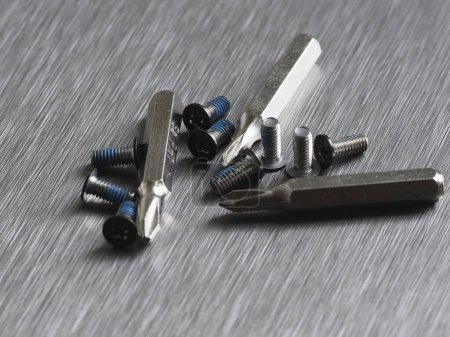 Tornillos y piezas de repuesto para un destornillador sobre fondo metálico gris