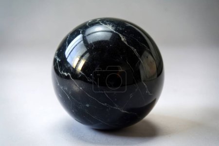 Bola de mármol negro con reflejos sobre un fondo claro