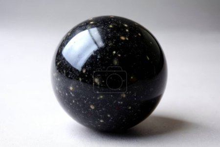 Bola de mármol negro con reflejos sobre un fondo claro