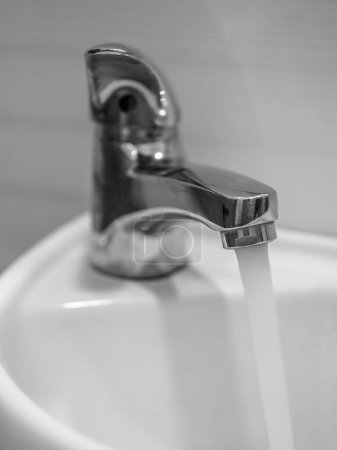 Photo for Faucet with water, metallic shine, white sink - Royalty Free Image