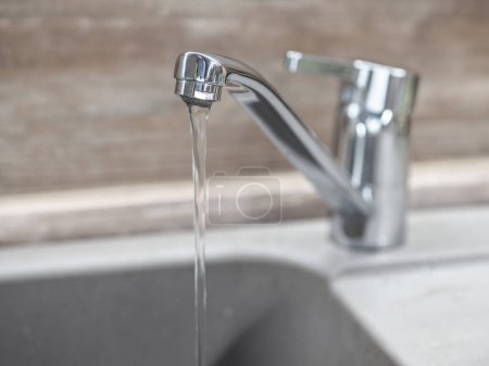 Faucet with water on the background of a wooden wall