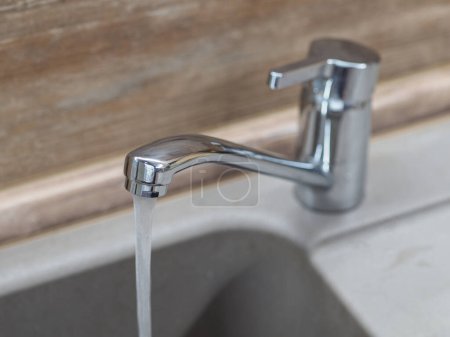 Faucet with water on the background of a wooden wall
