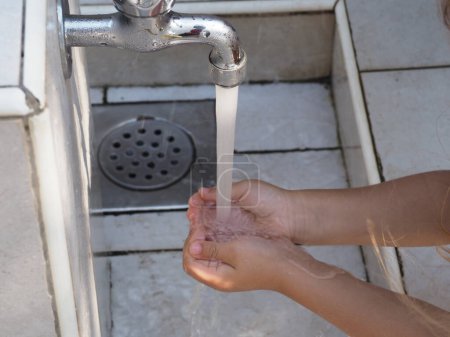 Ein kleines Mädchen wäscht sich in einem städtischen Pumpenhaus die Hände
