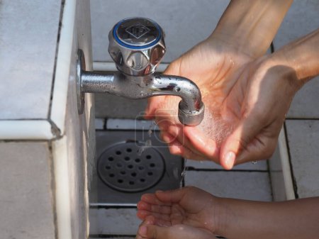 Ein kleines Mädchen wäscht sich in einem städtischen Pumpenhaus die Hände