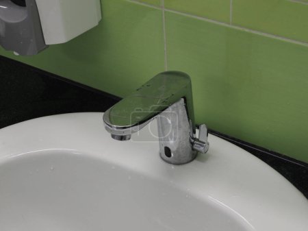 Sensor faucet for washing hands on a green background