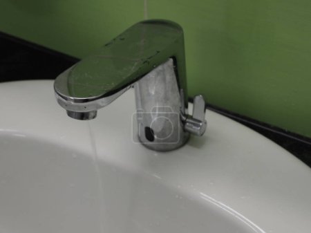 Sensor faucet for washing hands on a green background