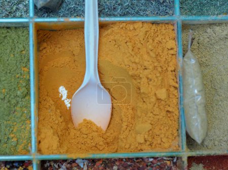 Vibrant Yellow Curcumin: Turmeric in an Old Metal Container with a White Spoon