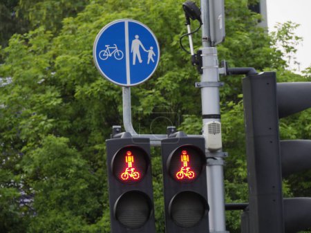 Rote Ampel für Radfahrer und Fußgänger gegen grünes Laub