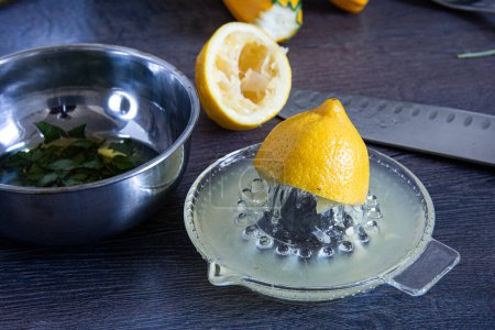 Photo for A citrus fruit, the lemon, is being juiced into a glass dishware container, to be used as an ingredient in a cuisine recipe in a mixing bowl - Royalty Free Image