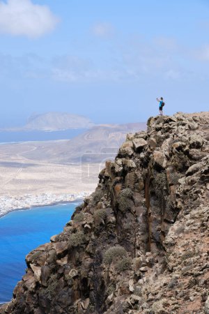 Foto de Mujer fotografiando el paisaje desde una colina. Isla La Graciosa al fondo. Islas Canarias - Imagen libre de derechos