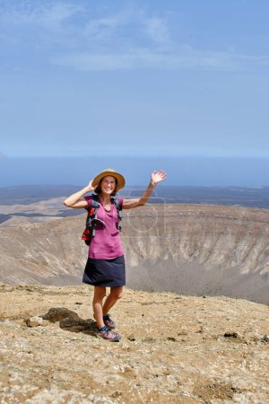 Photo for Happy woman climbing to the top of a volcano crater. Adventure vacation concept - Royalty Free Image