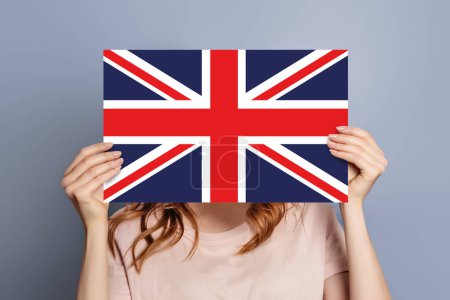 Student holds uk flag emblem speech bubble isolated over grey studio background. UK news concept